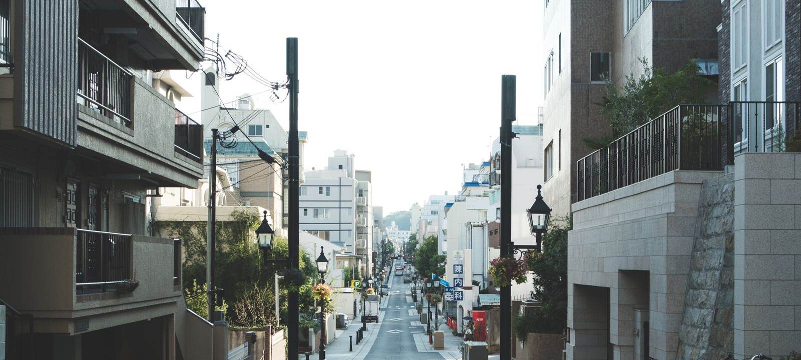 住宅と店舗が並ぶ通りを見通した朝の街並み