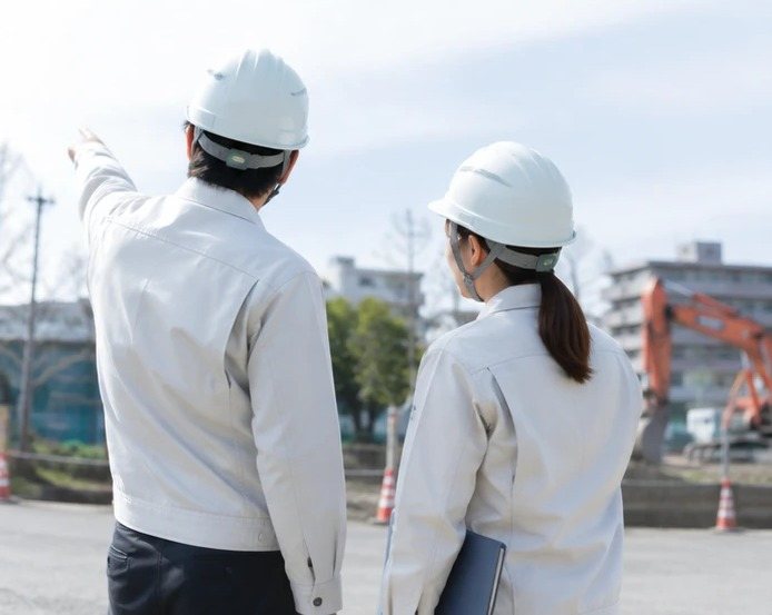 工事現場で現況を確認しながら打ち合わせる社員2名