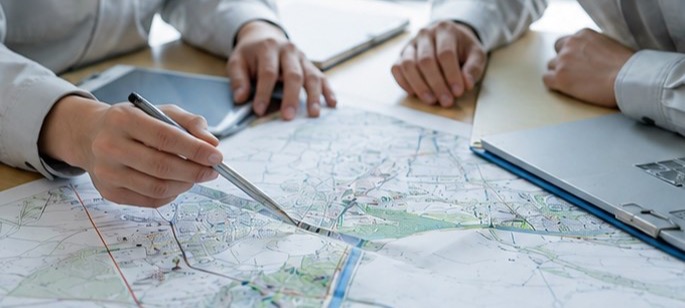 地図の上で計画箇所をペンで指し示す手元